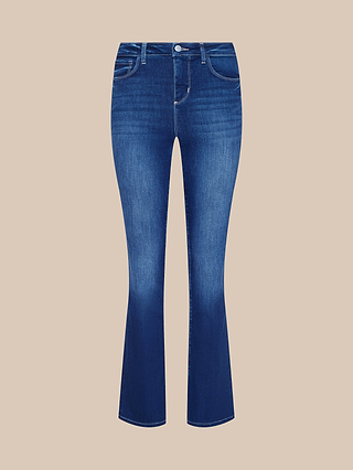 The Petite Selma Bootcut Jean from the Les Petites Collection is crafted from super stretch blue denim with a slight flare at the bottom, featuring a front button and zipper closure along with classic five-pocket styling, displayed on a beige background.
