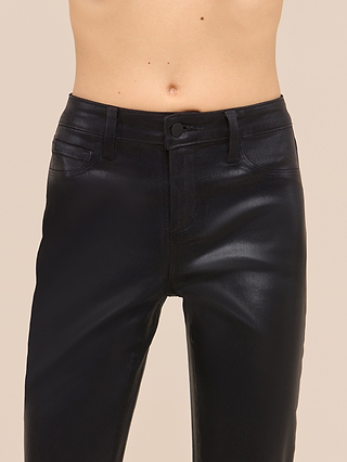 A person wearing the Petite Marty Coated Jean from the Les Petites Collection in black, styled high-waisted and photographed from the waist to mid-thigh against a neutral beige background, with their torso bare above the jeans.