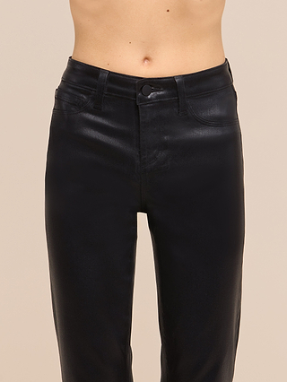 A person wearing the Petite Kendra Coated Jean from the Les Petites Collection in black, a high-rise, faux leather pant, shown from the waist to mid-thigh against a plain beige background.