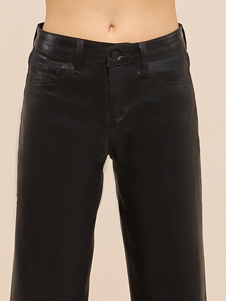 A person wearing the Petite Scottie Coated Jean from the Les Petites Collection in high rise black, shown from waist to mid-thigh against a neutral background. The jeans feature a button closure, belt loops, and visible front pockets. Their sleek coated finish offers a modern edge reminiscent of leather.