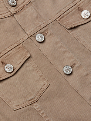 Close-up of the Anouk Jean Jacket, a collarless beige corduroy design with silver buttons and two flap chest pockets. The relaxed fit accentuates the fabric’s texture and detailed stitching.