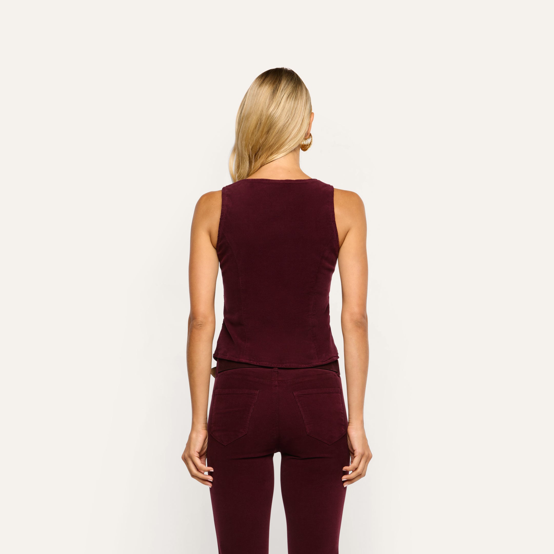 Back view of a person wearing a tailored maroon Yelena Corduroy Vest paired with matching stretch corduroy trousers.