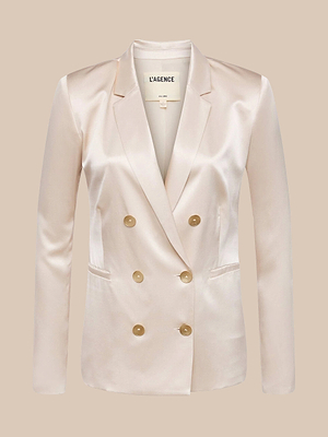 The Colin Silk Blazer is a light beige, satin-finish double-breasted blazer in silk charmeuse with tan buttons and notched lapels, shown on a neutral background.