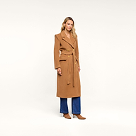 A person wearing the Kolina Long Coat, styled with blue jeans and tan heels, stands against a plain white background.