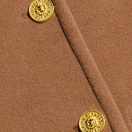 Close-up of the cognac brown Kolina Long Coat, crafted from Italian wool and detailed with two textured, round gold buttons featuring intricate designs.