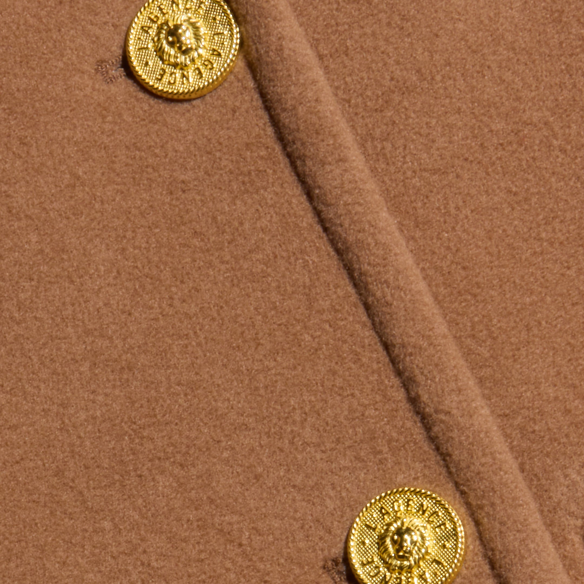 Close-up of the cognac brown Kolina Long Coat, crafted from Italian wool and detailed with two textured, round gold buttons featuring intricate designs.