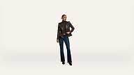 A woman wearing a black leather blazer, dark turtleneck, blue flared jeans, and heeled boots stands confidently against a plain white background.