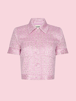 The Chita Tweed Jacket—a cropped, short-sleeve, button-up pink tweed shirt with collar and front pockets from the L’AGENCE Legally Blonde capsule—is showcased against a light pink background.