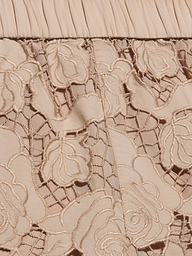 Close-up of almond tan fabric with floral lace embroidery and pleated detailing at the top edge. The lace features intricate flower patterns over a solid background, reminiscent of the delicate design found in the Laina Eyelet Short.