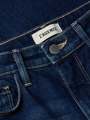 Primo piano del jeans Rosalyn Wide-Leg in denim elasticizzato blu scuro, con tasca frontale, bottone in metallo, passanti per la cintura ed etichetta LAGENCE bianca cucita sulla vita alta.