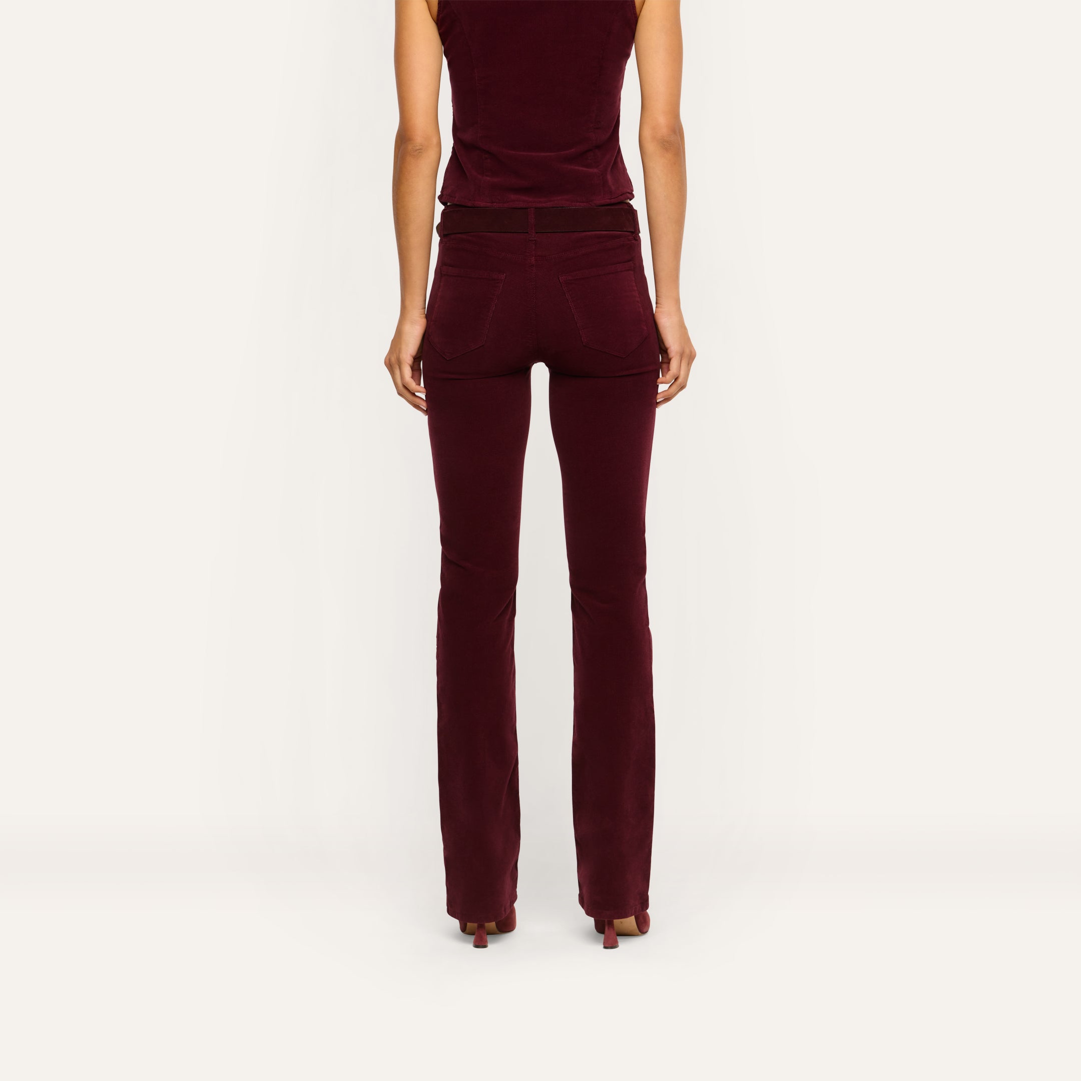 Back view of a person wearing fitted burgundy high-rise stretch corduroy Saffia Corduroy Pant and a matching sleeveless top.