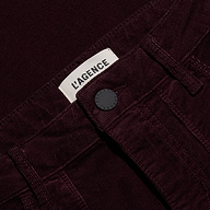 Close-up of the waistband of the burgundy Saffia Corduroy Pant, a slim-straight stretch style featuring a button closure and a brand label.