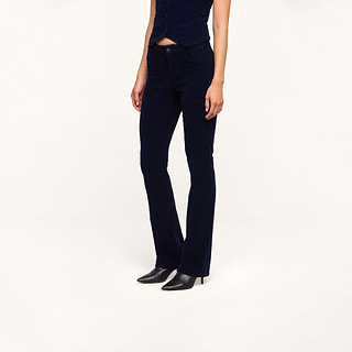 A person wearing a navy blue buttoned top and the Saffia Corduroy Pant with black pointed-toe boots, standing against a plain white background.
