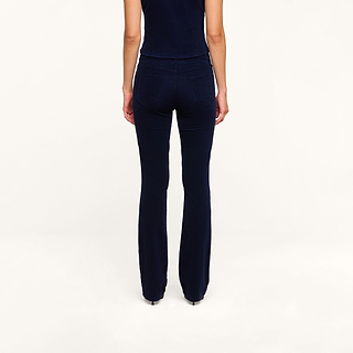 A person stands with their back to the camera, wearing a navy blue top and the Saffia Corduroy Pant against a plain white background.