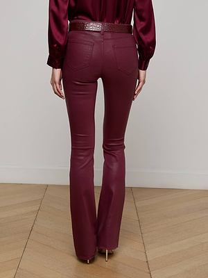 Back view of a person wearing L'AGENCE Ruth Coated Straight-Leg Jean in burgundy with a matching belt and satin long-sleeve blouse, standing on a light wood floor.