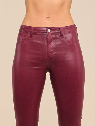 A person wearing Selma Coated Bootcut Jeans in shiny maroon, shown from waist to upper thighs, against a plain beige background.