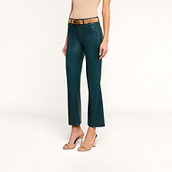 Une femme portant un jean évasé court enduit « Kendra » de couleur bleu sarcelle, assorti dune ceinture beige clair, dun haut sans manches beige et descarpins beiges à bout ouvert, se tient debout devant un fond beige uni.