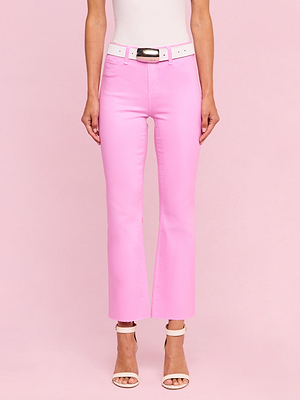 Wearing a white top, white belt, and the Kendra Coated Cropped Flare Jean in pink with white heeled sandals, a person stands against a pink background.