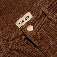 Close-up of cognac brown, high-rise Scottie Corduroy Wide-Leg Pant featuring a metal button and a label reading LAGENCE.