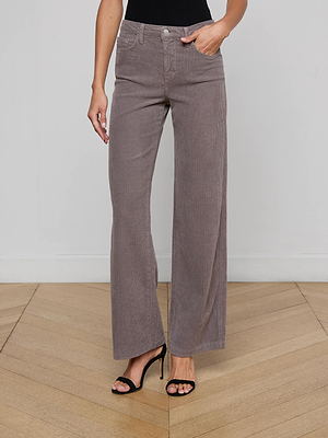 Someone wearing the Scottie Corduroy Wide-Leg Jean in taupe with a contoured waistband, a black sleeveless top, and black high-heeled sandals stands on a light wooden floor against a plain white wall.