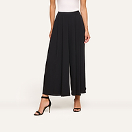 A woman wears the Novalynn Cropped Pleated Pant, a white sleeveless top, and black high-heeled sandals, standing against a plain light background.