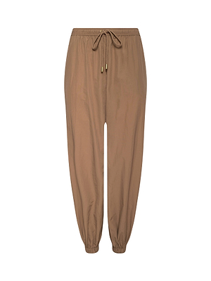The Mariko Jogger is a light brown, modern pant made from lightweight nylon with an elastic waistband, drawstring tie, and elastic ankle cuffs. Shown against a white background.