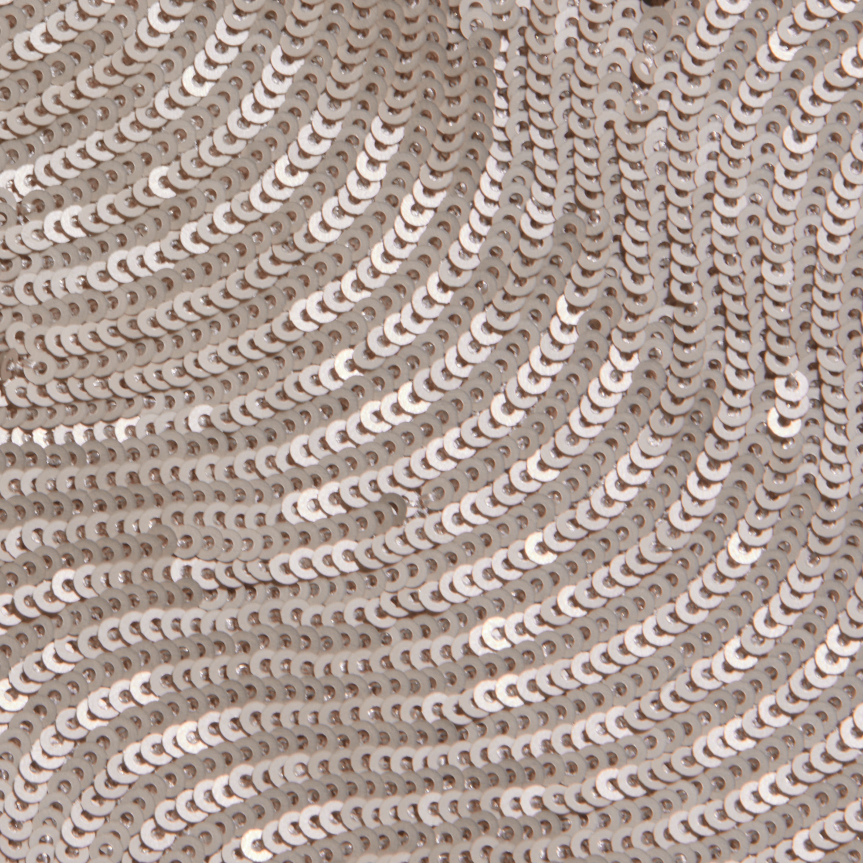 Close-up of shiny, champagne sequins sewn onto fabric in swirling, wave-like patterns creates a textured and reflective surface—perfect for special occasions or elevating your look with the elegant Zeta Sequin Maxi Skirt.