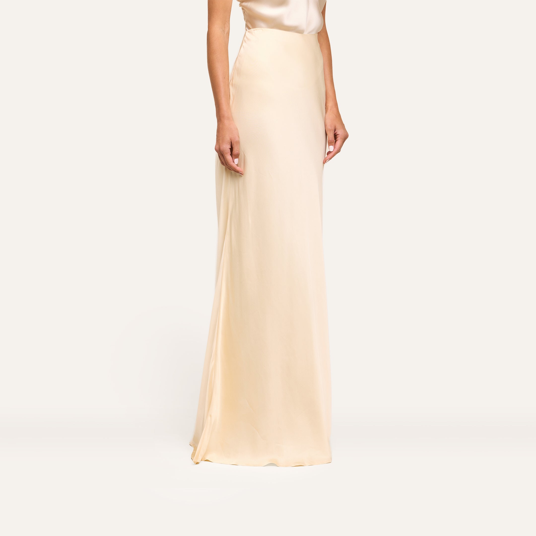 Wearing the Zeta Satin Maxi Skirt and a matching sleeveless top, the person stands against a plain, light background, shown from shoulders to feet.