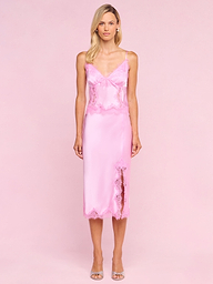 A woman stands against a white background wearing the Tico Silk Lace Skirt, styled with open-toe heels.