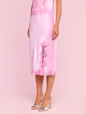 A person in the Tico Silk Lace Skirt from the Legally Blonde collection and silver open-toe heels stands against a pale pink background.