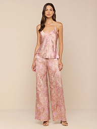 A woman stands against a plain white background wearing the Lexi Silk Camisole in pink paisley satin, featuring adjustable straps, paired with matching wide-leg pajama pants and heeled sandals.