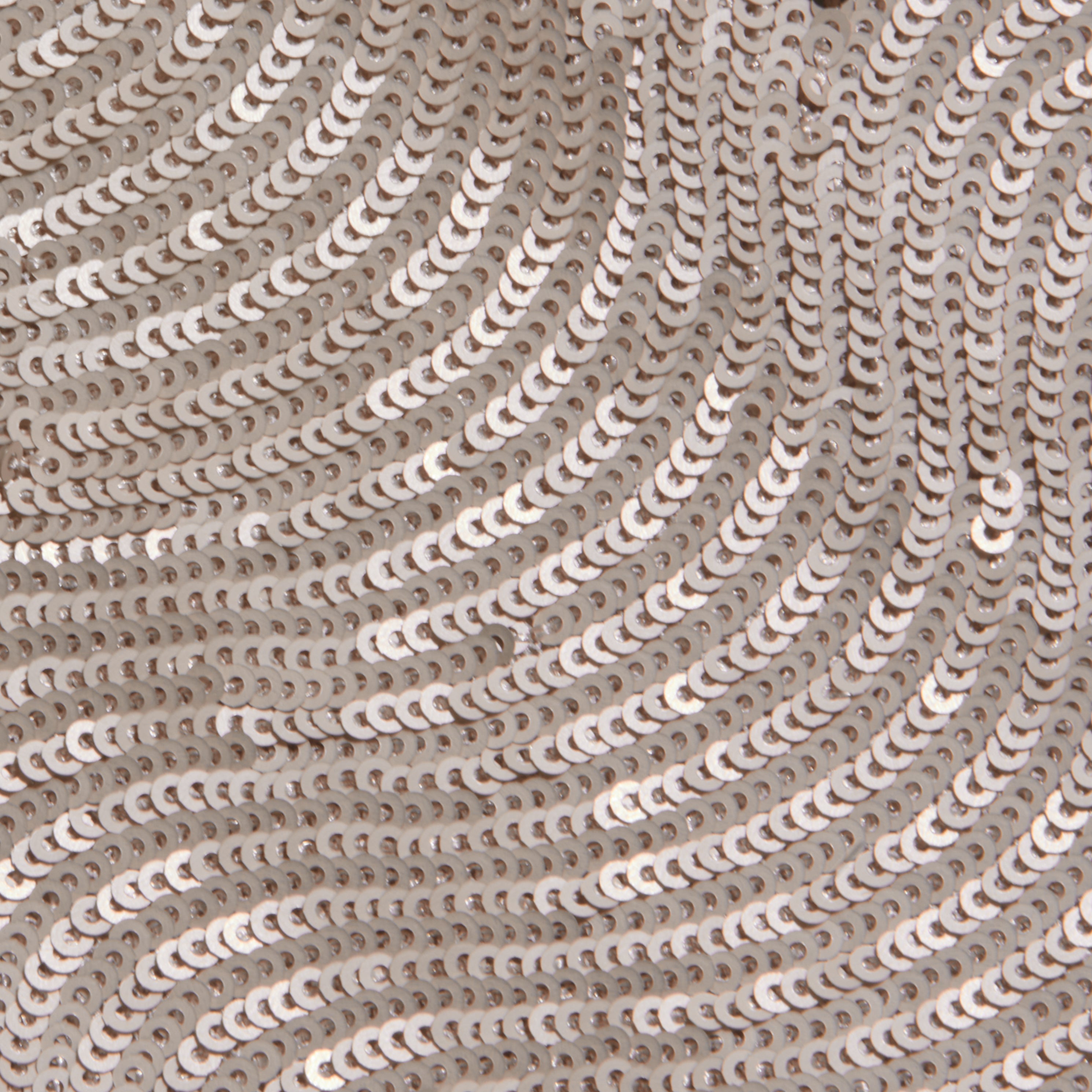 Close-up of the Rogan Sequin Top, featuring party-ready, shiny silver sequins sewn in swirling wave-like patterns on a light fabric background.