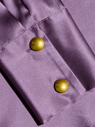 Close-up of the Honey Silk Blouse’s lustrous lavender cuff, adorned with two gold buttons engraved with LAGENCE. The piece is crafted from sumptuous silk charmeuse, showcasing a smooth texture that shimmers beautifully in the light.