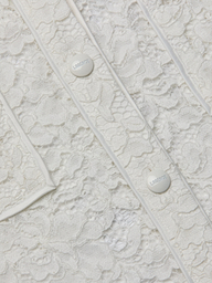Close-up of the Roelle Lace Blouse in white, showcasing its intricate floral lace patterns, two white buttons engraved with “LARENTE,” and delicate piping details. The romantic texture and fine design elements of this blouse are clearly visible.