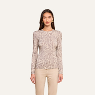 A woman wears the Tess Long Sleeve Tee, featuring a slim fit and subtle grey leopard print, paired with beige pants and set against a plain off-white background.
