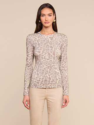 A woman stands facing forward, wearing the Tess Long Sleeve Tee in a beige leopard print paired with light beige pants, against a neutral background.