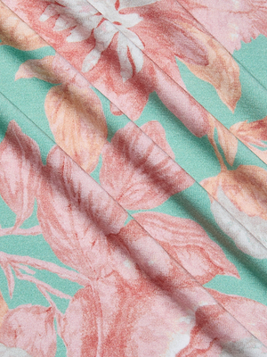Close-up of the Ressi Fitted Tee's pastel floral print, showcasing pink and peach flowers with green leaves on a light turquoise background. The tee features soft folds and a smooth texture.