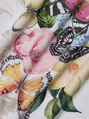Close-up of the Ressi Fitted Tee, showcasing a colorful butterfly print with pink and yellow flowers and butterflies in orange, black, and yellow on a white stretch jersey knit background.