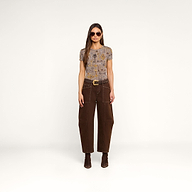 A woman wearing sunglasses, the bestselling Ressi Fitted Tee with a patterned short-sleeve design, brown high-waisted wide-leg pants, and brown boots stands facing forward against a plain white background.