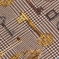 Several ornate vintage keys, both gold and black, are arranged diagonally on a textured brown houndstooth fabric background featuring the Ressi Fitted Tee.