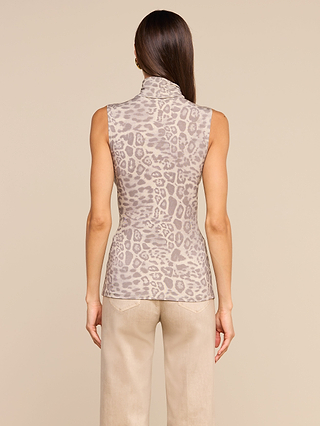 A woman with straight brown hair is seen from behind, wearing the Ceci Sleeveless Turtleneck in a slim fit with a light gray leopard print, paired with beige pants, standing against a plain tan background.