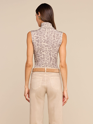 A woman faces away, wearing the Ceci Sleeveless Turtleneck in a slim fit light gray leopard print, paired with light beige pants against a plain, neutral background.