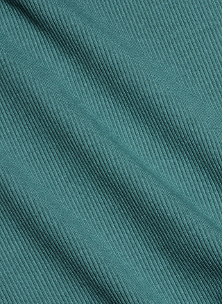 Close-up of teal-colored ribbed fabric with diagonal lines and subtle folds, highlighting the texture and pattern of the material used in the Nica Scoopneck Bodysuit—ideal for creating a comfortable base layer or sleek silhouette.