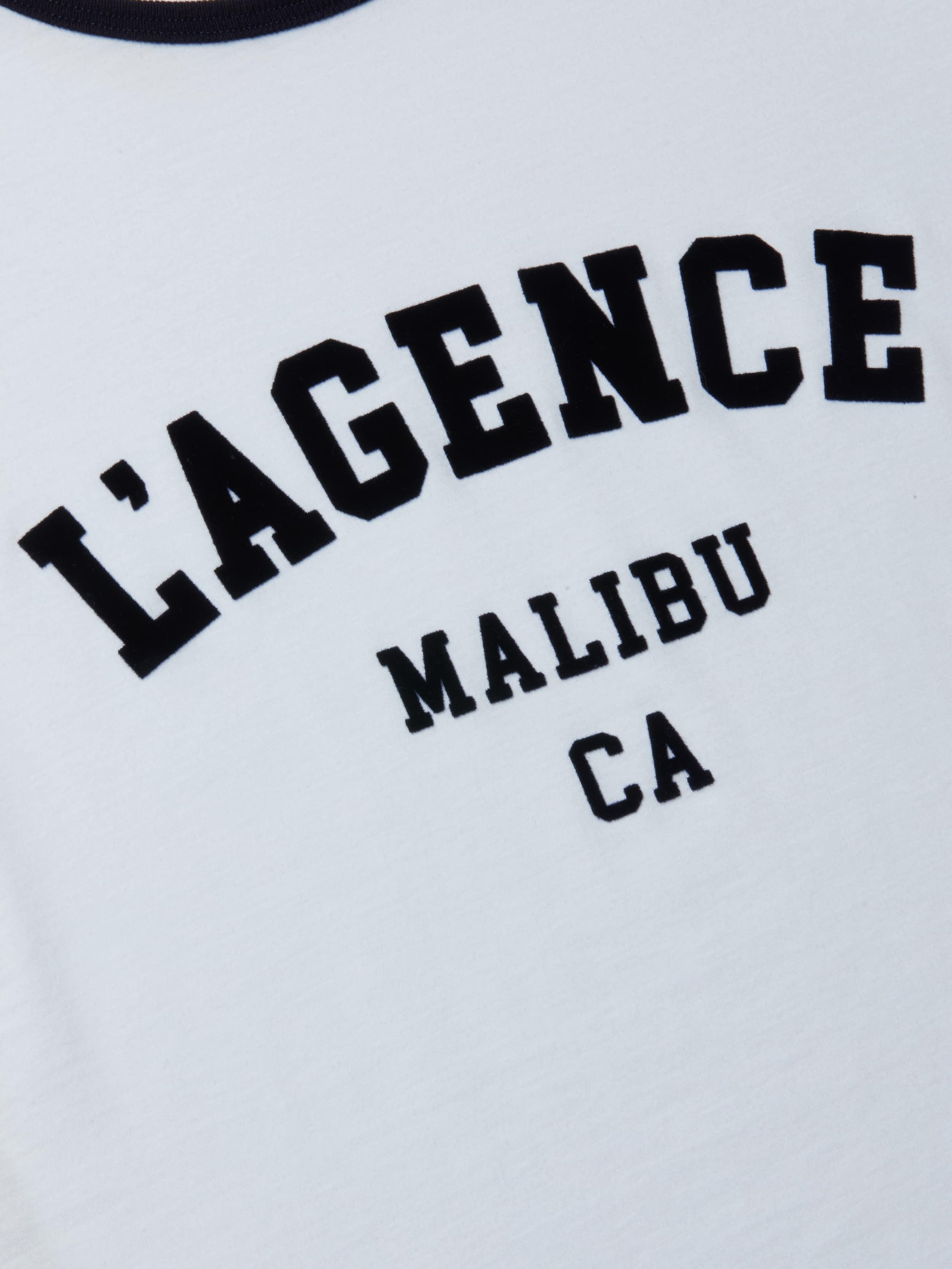 Close-up of the Tommie Crewneck Tee, a white ringer made from soft Supima cotton, featuring bold black LAGENCE MALIBU CA text in an athletic collegiate font.