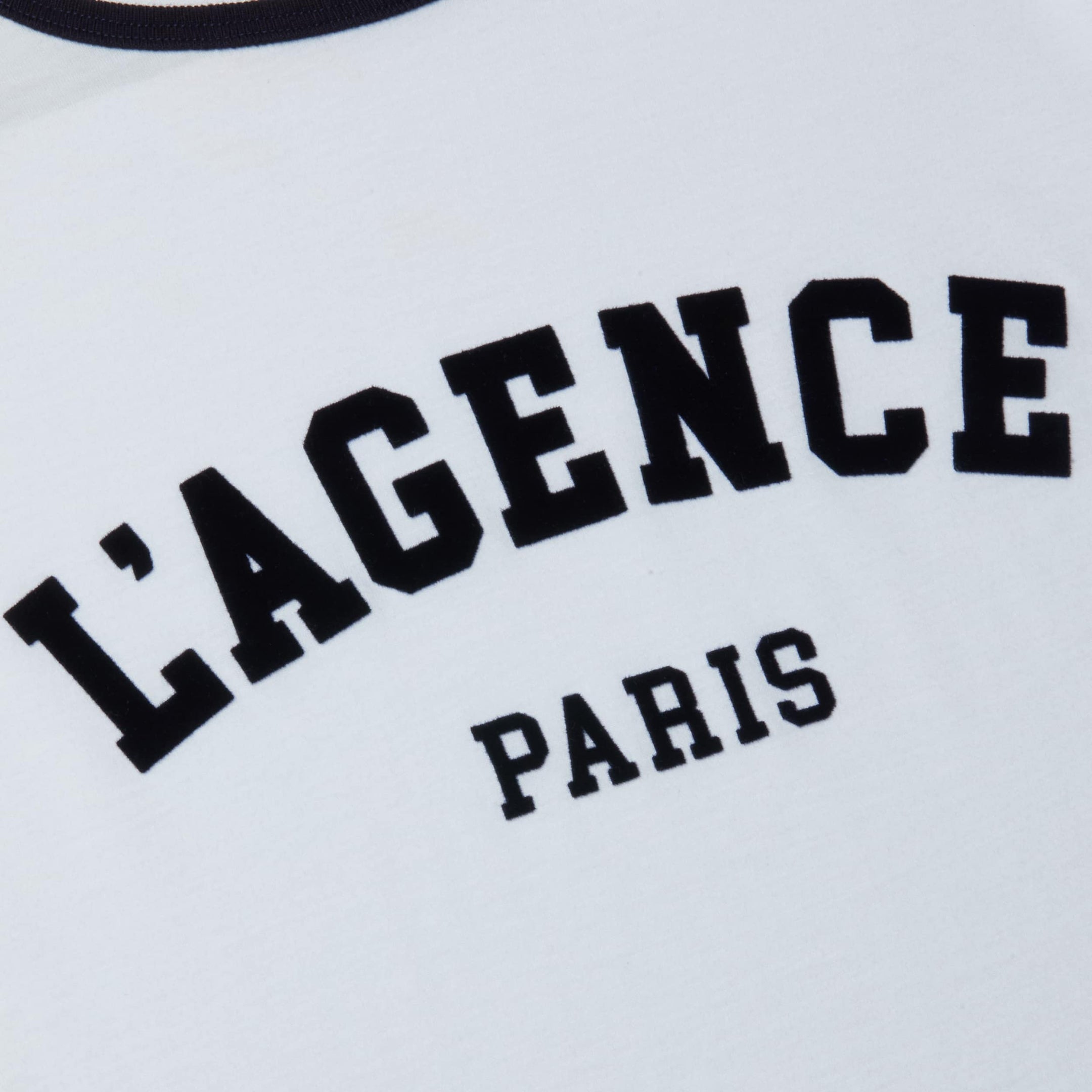 A close-up of the Tommie Crewneck Tee, crafted from white Supima cotton and featuring bold, collegiate-style black text that reads LAGENCE PARIS.