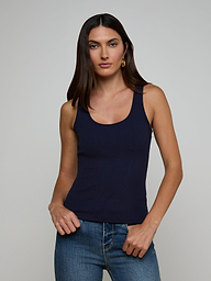 A woman with long dark hair wears the Adira Scoopneck Tank in navy blue and blue jeans, standing against a plain light background, looking at the camera with a neutral expression.