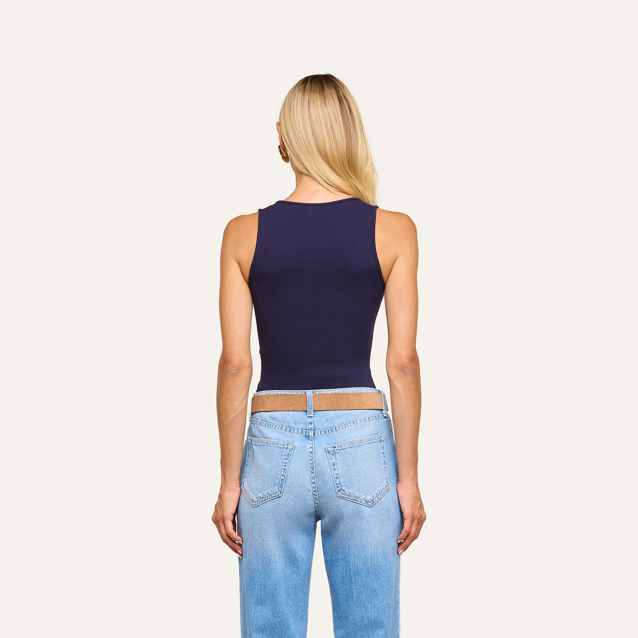Woman with long blonde hair wears the Adira Scoopneck Tank in navy and light blue jeans, standing with her back to the camera against a plain light background.