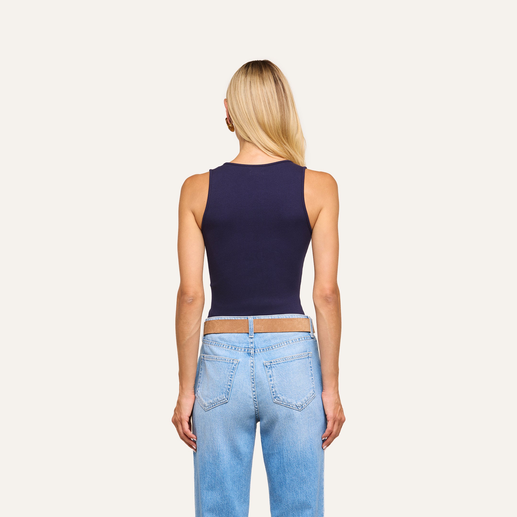 Woman with long blonde hair wears the Adira Scoopneck Tank in navy and light blue jeans, standing with her back to the camera against a plain light background.