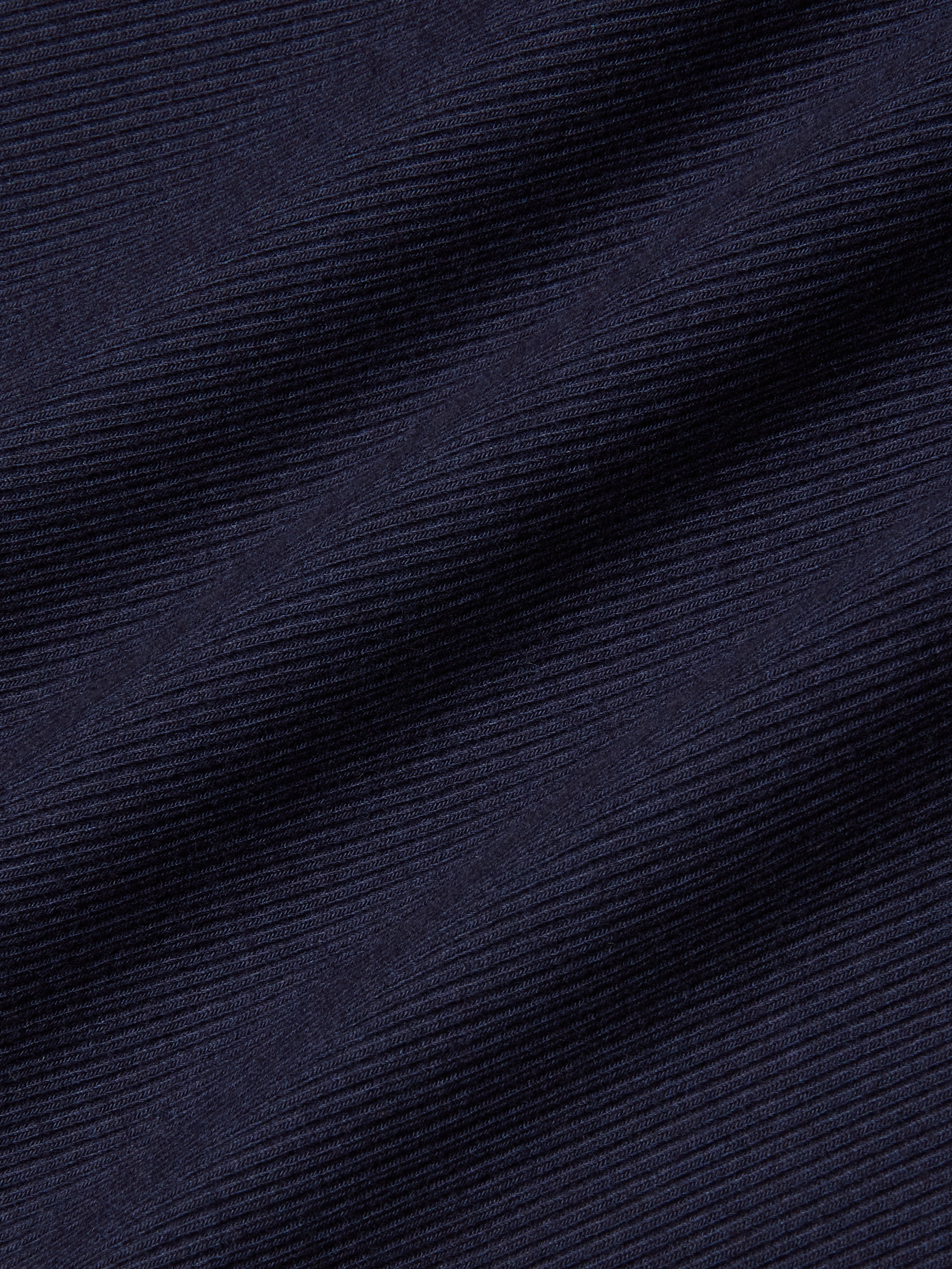 Close-up of the Adira Scoopneck Tank in dark navy blue stretch rib fabric, featuring diagonal textured lines with fine horizontal ridges and subtle light reflections.