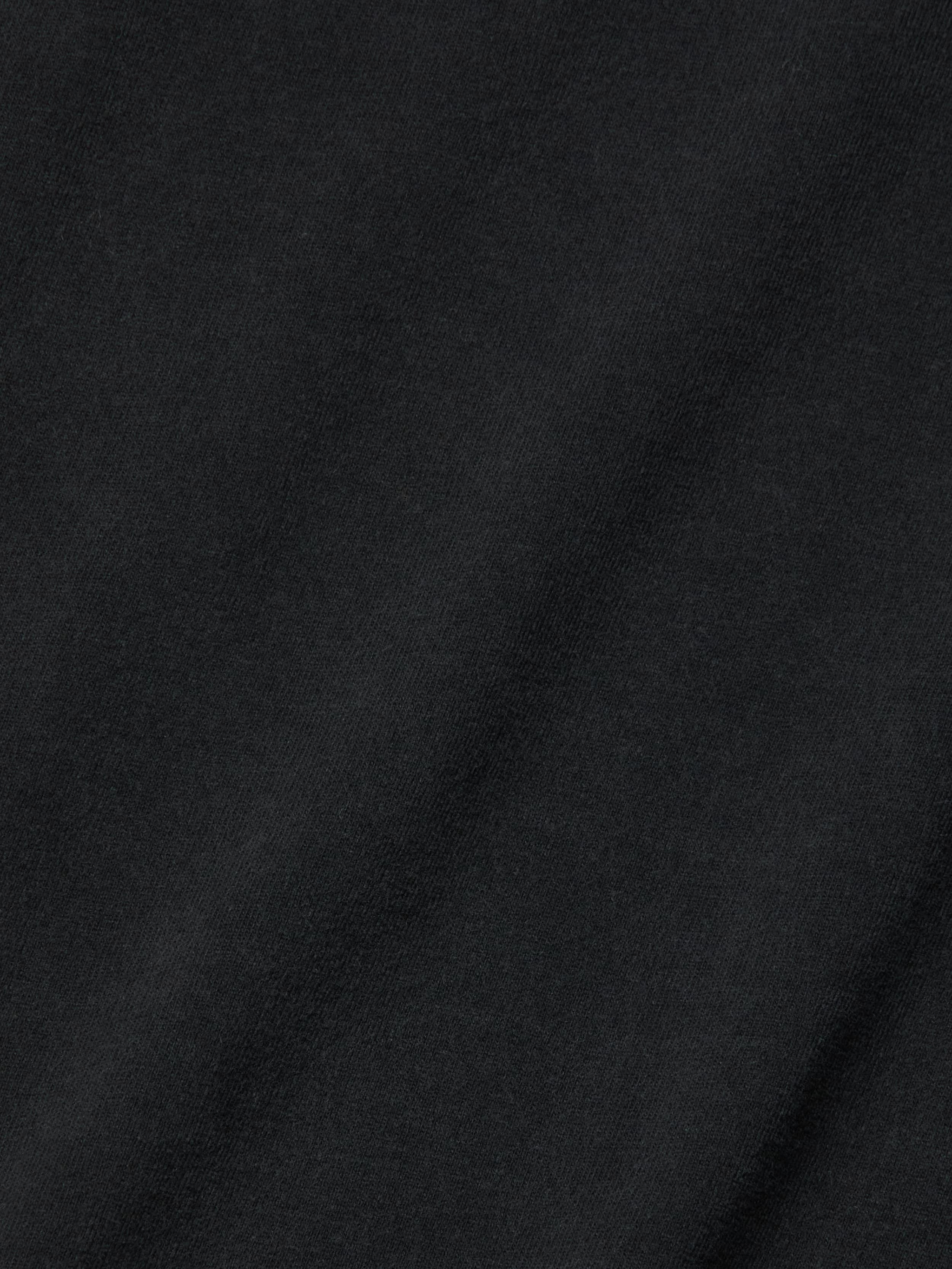 Close-up view of the Daria Oversized Cropped Tee in black, crafted from Supima cotton with a subtle diagonal weave pattern and a soft texture, accented by gentle shadows and highlights.